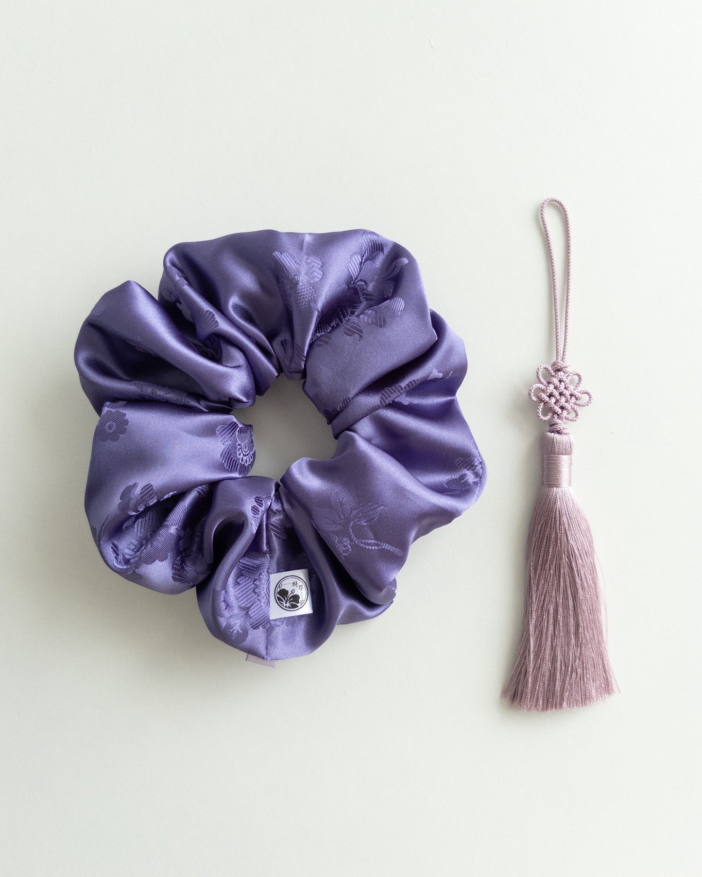 Purple hanbok scrunchie with a norigae(tassel) on a light background