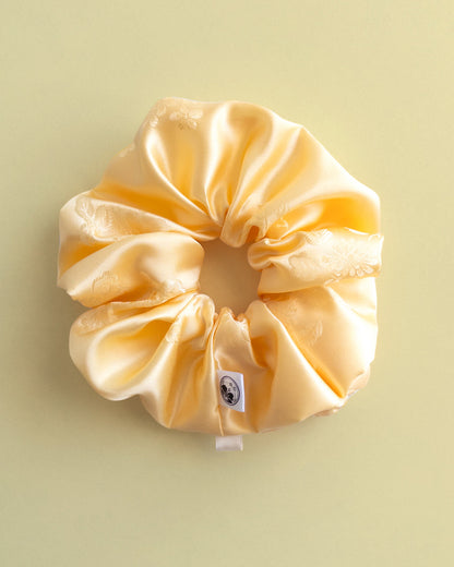 Yellow satin hanbok scrunchie on a light green background