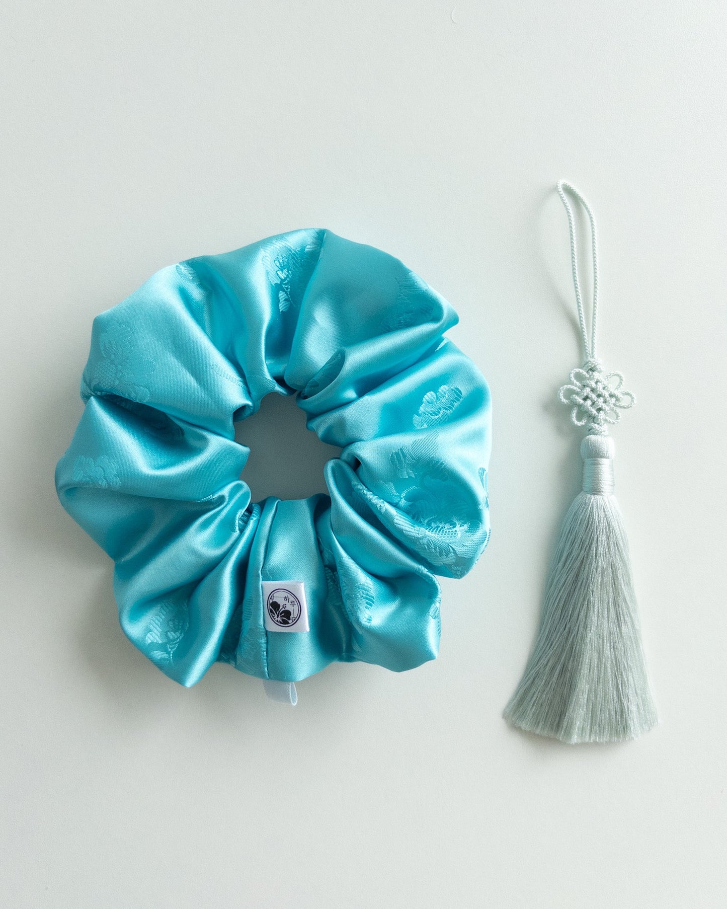 Blue scrunchie with a tassel on a light gray background