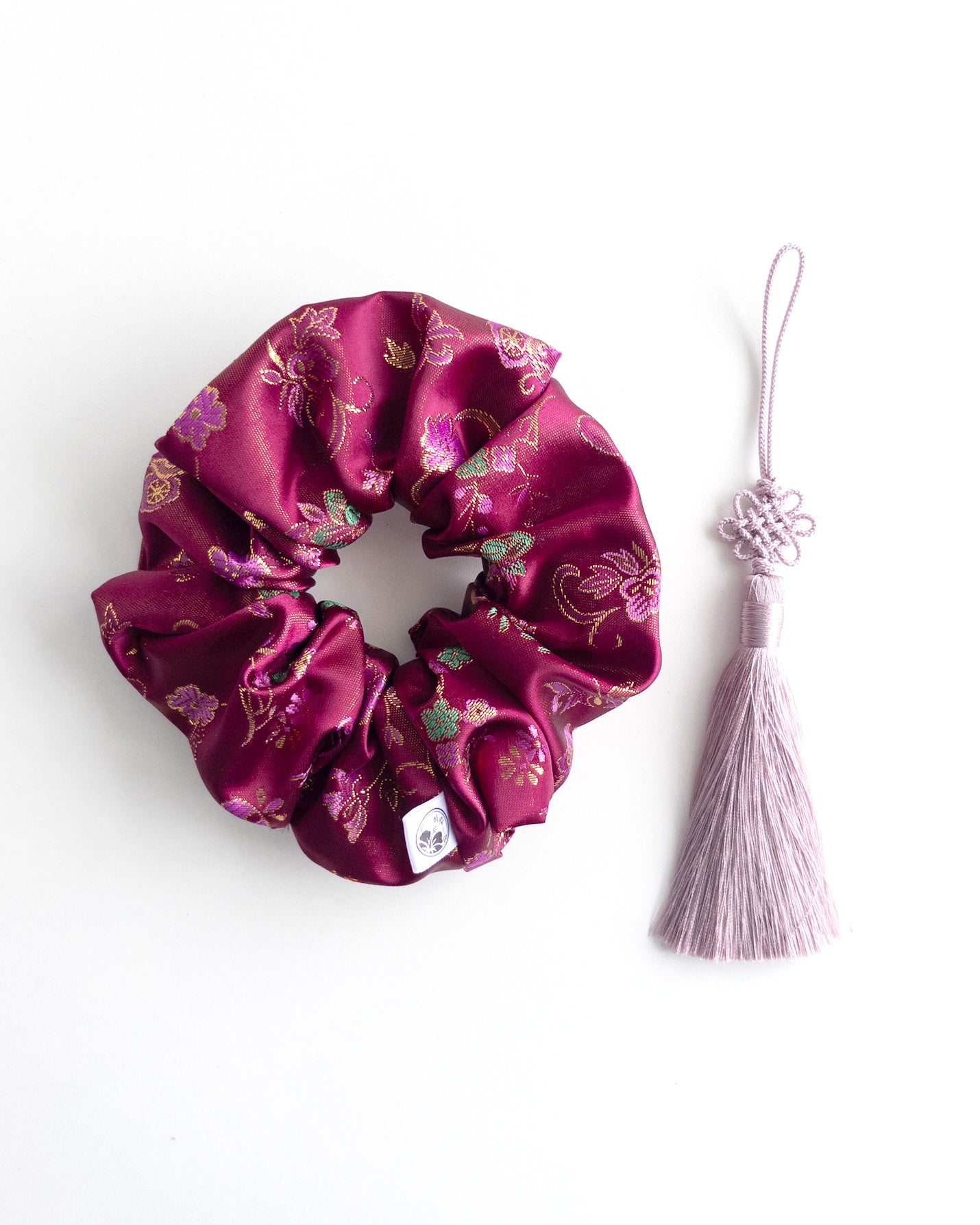 Purple floral scrunchie with a norigae on a white background